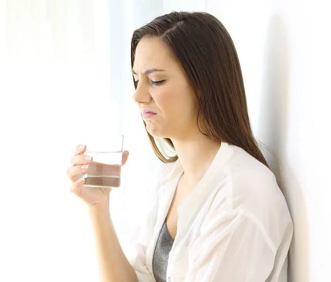 Woman grimacing after tasting a glass of water
